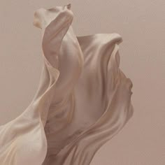 an abstract photograph of white fabric blowing in the wind on a beige background with neutral tones