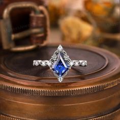 a blue and white diamond ring sitting on top of a wooden box