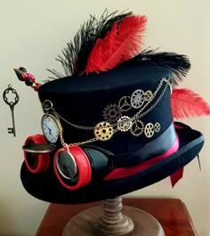 Hats come in size S=55cm-56cm, M=57cm-58cm, L=59cm-60cm, & XL=61cm-62cm please message what size you require when ordering.  Steampunk black 100% wool hard top hat sized fully lined in satin. Red & black goggles with clock wheel inside one lens & a monocle on other lens with chain trapped over hat. A large real pocket watch sits on front with chain trapping over hat. Various clock wheels on one side & red & black ostrich feathers on other side. 2 x gold hatpins with red, gold & black pearls & be Black Goggles, Steampunk Black, Steampunk Top, Steampunk Couture, Mad Hat, Steampunk Top Hat, Arte Monster High, Steampunk Hat, Satin Noir