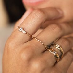 a close up of a person's hand with three different rings on their fingers