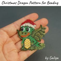 a hand holding a christmas dragon pattern for beading