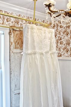 a white dress hanging on a clothes line in front of a wallpapered room