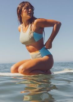 a woman is sitting on a surfboard in the water