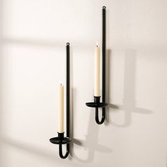 two candles are hanging on the wall next to each other with one candle in between them