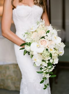 a bride holding a bouquet of white and pink flowers on her wedding day at the hotel