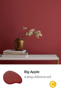 a vase with flowers sitting on top of a table next to books and a red wall