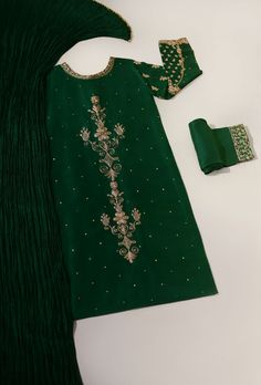 Adorned on pure raw silk 58 Gms, in a deep emerald green hue intricately hand embellished with dabka, zari, naqshi and sequins. The length of the long kameez is 46 inches. Accompanied with matching trousers and pure silk crushed dupatta featuring handmade buttons. An alluring three piece with old world charm, perfect f Green Kurta With Naqshi In Traditional Drape, Green Kurta With Naqshi And Traditional Drape, Green Churidar With Mirror Work In Traditional Drape, Green Churidar With Mirror Work, Elegant Designer Green Churidar, Elegant Green Churidar With Straight Kurta, Green Fitted Kurta With Naqshi, Designer Green Churidar With Mirror Work, Festive Green Raw Silk Churidar