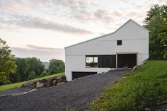 a white barn sitting on top of a lush green hillside