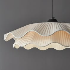 a light that is hanging from the ceiling with pleated fabric on it's sides