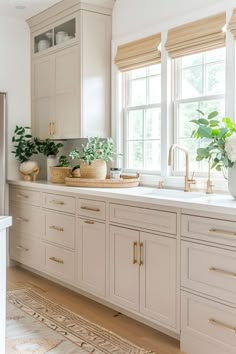 a kitchen filled with lots of white cabinets and counter top space next to a window