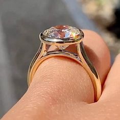 a close up of a person's hand holding a ring with a large diamond on it