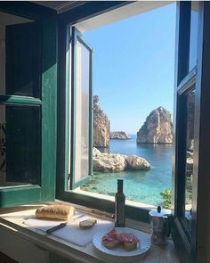 there is a plate of food on the window sill next to the water and rocks