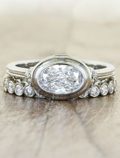 a close up of a diamond ring on a wooden surface with other rings around it