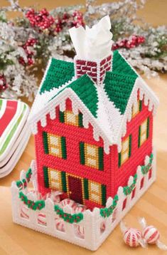 a red and white house made out of legos on a table next to candy canes