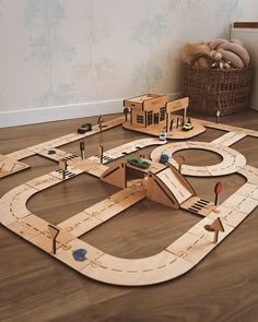 a wooden toy train set sitting on top of a hard wood floor next to a basket