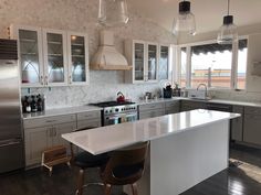 a large kitchen with stainless steel appliances and white counter tops is pictured in this image