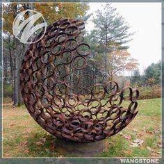 a large metal object sitting on top of a lush green field in front of trees