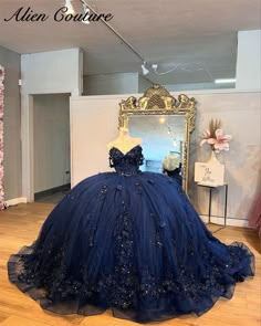 a blue ball gown sitting on top of a wooden floor in front of a mirror