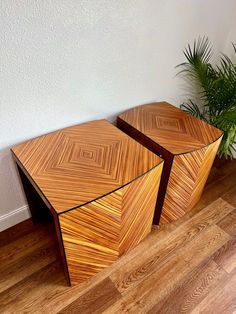 two wooden tables sitting on top of a hard wood floor next to a potted plant