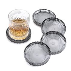 four clear glass coasters with black rims and gold accents on each one side