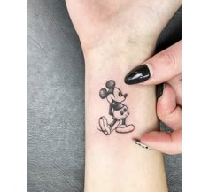 a person with a mickey mouse tattoo on their wrist