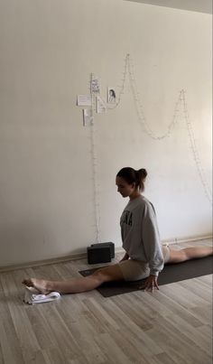 a woman is sitting on the floor with her feet up and looking at something in front of her