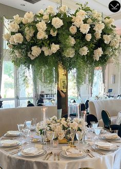 a table set with white flowers and place settings