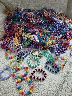 a pile of beads and bracelets laying on the floor next to a white blanket