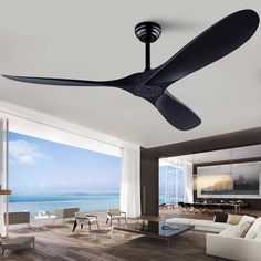 a living room with a ceiling fan and large windows overlooking the ocean in front of it