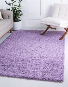 a living room with a white chair and purple rugs on the floor in front of a couch