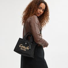 Carry as much (or as little) as you like with our lightweight Cargo tote. Detailed with our cursive Coach script embroidery and iconic turnlock closure this compact 26 has an open interior with room for an iPad two outside pockets for easy organization and a removable webbing strap for shoulder or crossbody wear. Crafted to last this versatile carryall is made with cotton sourced from farms that use regenerative agricultural practices* and inspired by our commitment to reducing our impact on the Luxury Calvin Klein Shoulder Bag, Luxury Calvin Klein Shoulder Bag For Everyday, Luxury Everyday Calvin Klein Shoulder Bag, Coach Handbags Coach, Everyday Calvin Klein Shoulder Bag, Coach Bags Handbags 2022, Coach Bags Handbags Coach, Coach Hamdbags, Theo Tote Coach