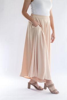 Be the talk of every room with our Keep it Glowing - Woven Wide Leg Pants! These champagne, satin pants are beyond gorgeous. They give the illusion of a skirt, but bring the comfort of pants. This item has a high waist, elastic waist band, and pockets. We love these so much because you can throw on a blouse to dress them up, or a tank to dress them down. You can wear these for any occasion and be the most stylish gal in the room! - Champagne colored woven wide leg pants - High waist - Elastic wa Versatile Solid Color Maxi Skirt With Elastic Waistband, Versatile Pleated Skirt Bottoms For Summer, Versatile Pleated Skirt For Summer, Spring High Waist Pants With Banded Waist, High Waist Pants With Banded Waist For Spring, Versatile Long Skirt With Lined Detail, Elegant Beige Bottoms With Elastic Waistband, Beige Long Skirt With Lining, High Waist Beige Pleated Skirt Bottoms