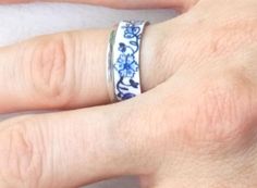 This ring is inspired by antique Delftware from Holland. The deep blue floral design on a white background is timeless and versatile, blending well with outfits from jeans through sundresses. The classic, beloved blue/white color combination looks great on any skin tone. This is a detailed, unique ring that is sure to be noticed! My original hand drawn and painted design is dyed and heat sealed by me on this aluminum ring. It is extremely durable; the process allows the colors to become part of Adjustable Bohemian Blue Flower Ring, Handmade Blue Wedding Rings, Handmade Blue Flower Ring For Anniversary, Handmade Blue Promise Ring, Elegant Blue Adjustable Flower Ring, Elegant Adjustable Blue Flower Ring, Handmade Blue Open Ring, Blue Sterling Silver Promise Flower Ring, Blue Sterling Silver Promise Ring