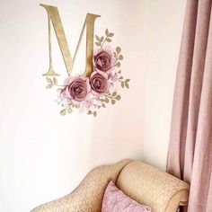 there is a chair with pillows on it in front of the letter m wall decal