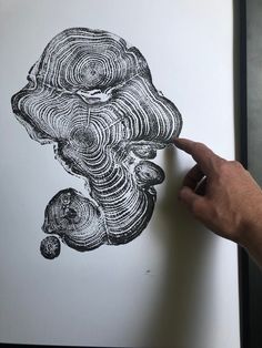 a hand is pointing at an ink drawing