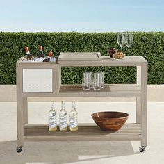 an outdoor bar cart with bottles and glasses on it