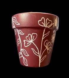 a red flower pot with white flowers painted on it