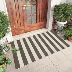 the front door is decorated with potted plants and an entrance mat that has been striped in black and white