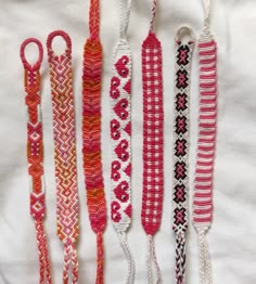 five different types of beaded bracelets on a white cloth with pink, orange and black beads