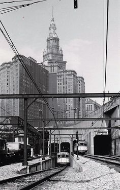 an old black and white photo of a train station in the city with buildings behind it