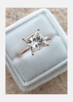 an engagement ring with a princess cut diamond in it's setting on a velvet box