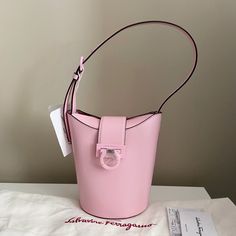 Brand New With Tags And Dust Bag Trifolio Shoulder Bucket Bag From Salvatore Ferragamo Featuring Light Pink Smooth Calf Leather, Adjustable Shoulder Strap, Gold-Tone Hardware, Engraved Logo, Gancini Flip-Lock Fastening, Main Compartment And Internal Card Slots. Depth: 10cm Handle: 25cm Height: 20cm Width: 18cm Designer Style Id: 211194 754435 Composition: Outer: Calf Leather 100% Lining: Leather Color: Light Pink Hardware: Light Pink Metal Made In Italy Designer Bucket Bag With Removable Pouch, Designer Leather Bucket Bag, Designer Bucket Bag, Luxury Pink Top Handle Bucket Bag, Pink Bucket Bag With Detachable Handle For Formal Occasions, Luxury Pink Bucket Bag For Shopping, Pink Formal Bucket Bag With Detachable Handle, Pink Rectangular Bucket Bag For Formal Occasions, Formal Pink Bucket Bag With Detachable Handle