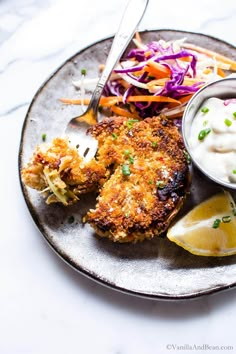 a plate with some food on it and a fork next to the plate is garnished with coleslaw