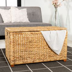 a living room with a gray couch and wicker storage box