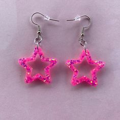 lightweight handmade star shaped resin earrings - made with a vibrant pink glitter that has reflects of orange, blue and green Pink Star Charm Dangle Earrings, Pink Dangle Earrings With Star Charm, Trendy Pink Star-shaped Jewelry, Trendy Pink Glitter Earrings, Pink Star Earrings For Party, Pink Star-shaped Jewelry For Party, Pink Star-shaped Party Earrings, Cute Pink Glitter Earrings, Handmade Pink Star-shaped Jewelry