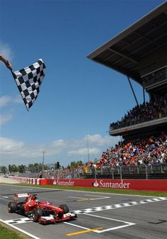 a man flying a checkered flag on top of a race car