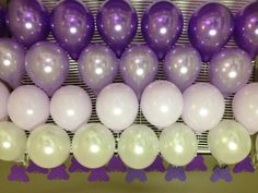 purple and white balloons are hanging on the wall