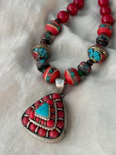 A beautiful Tibetan-Nepali style silver-plated vintage pendant with coral and turquoise exudes a unique and captivating ethnic charm. Traditional Turquoise Necklace With Large Pendant, Traditional Turquoise Necklace With Large Pendant As Gift, Traditional Handmade Turquoise Pendant Necklace, Traditional Turquoise Necklace For Festivals, Handmade Multicolor Turquoise Amulet Necklace, Traditional Multicolor Handmade Turquoise Necklace, Traditional Handmade Turquoise Necklace, Traditional Multicolor Turquoise Necklace For Festival, Traditional Turquoise Necklace With Natural Stones For Festivals