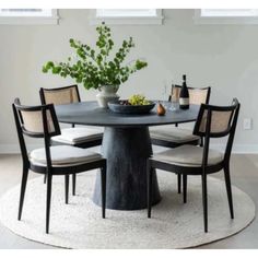 a round dining table with four chairs and a bowl of fruit on the centerpiece