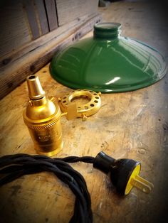 a green lamp sitting on top of a wooden table next to a black cord and plug